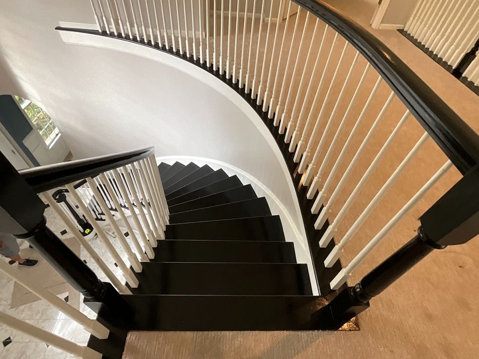 A curved staircase with black steps and white railings