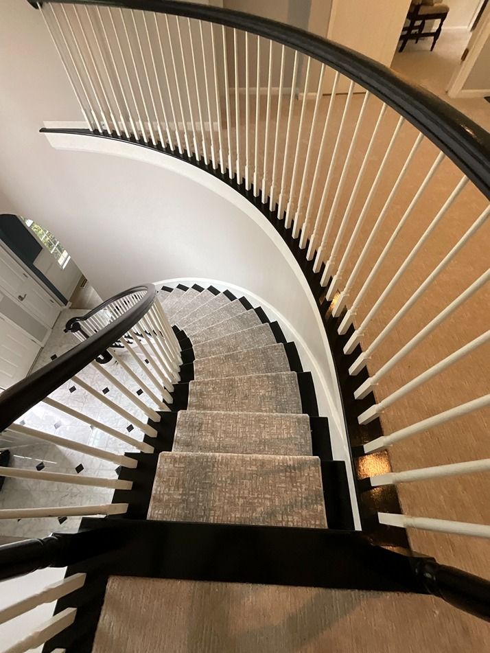 A spiral staircase with a black railing and a carpeted floor
