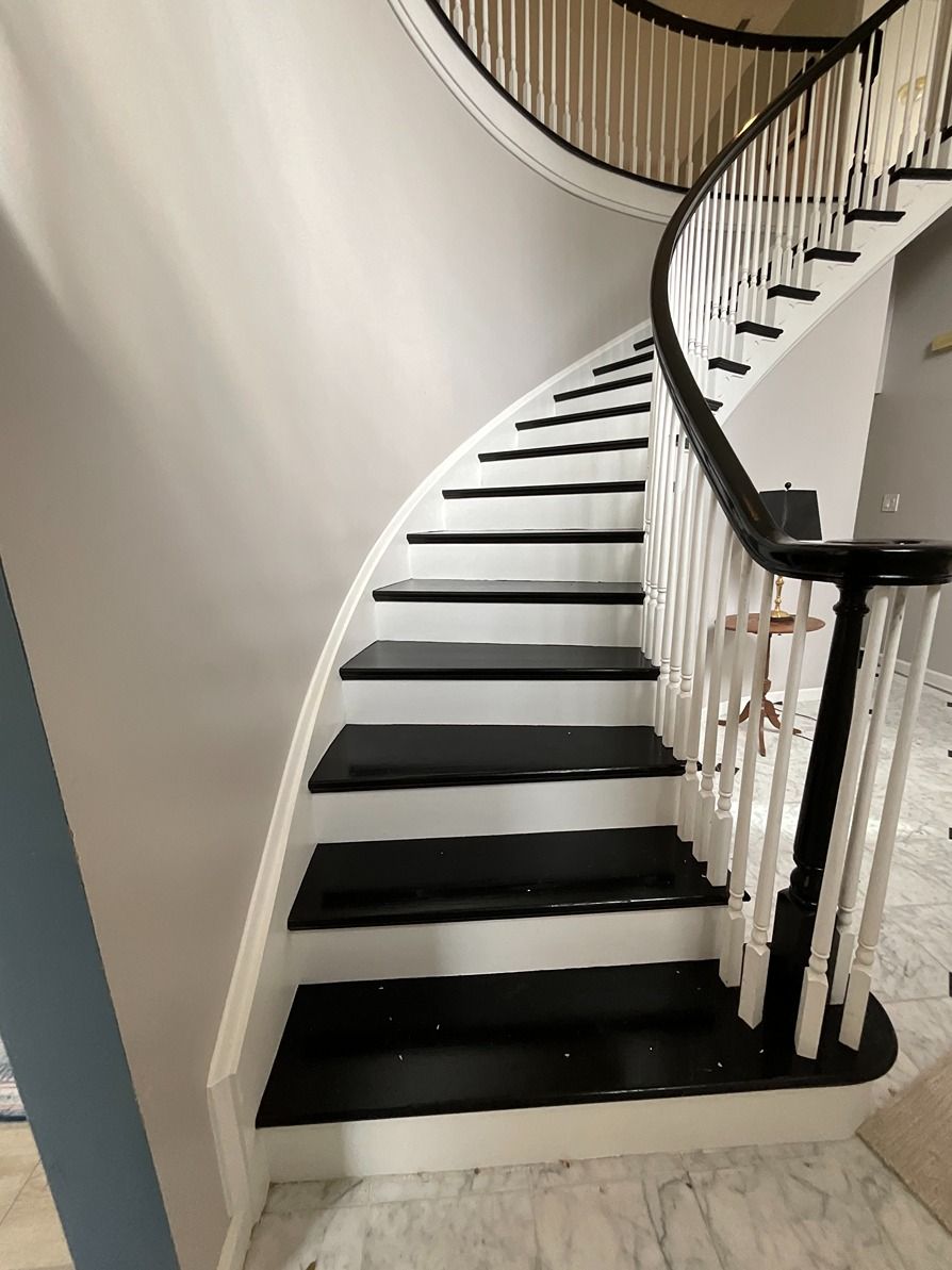 A spiral staircase with black steps and a white railing