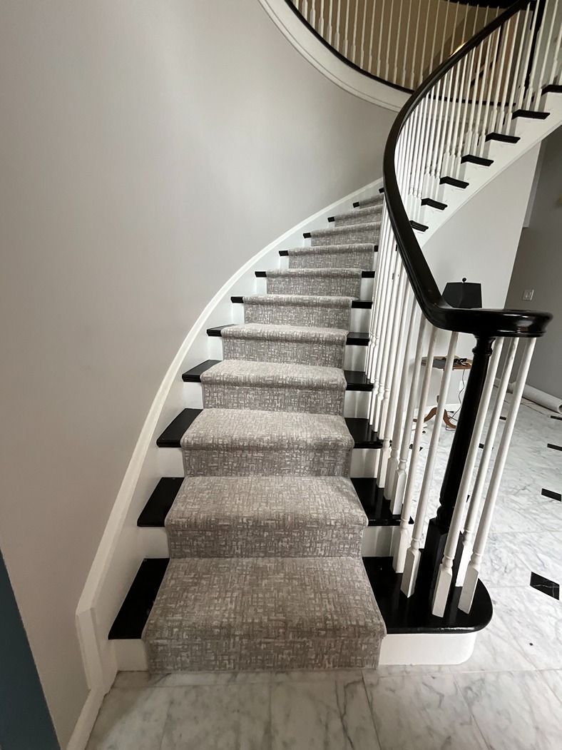 A curved staircase with a carpeted staircase and a black railing.