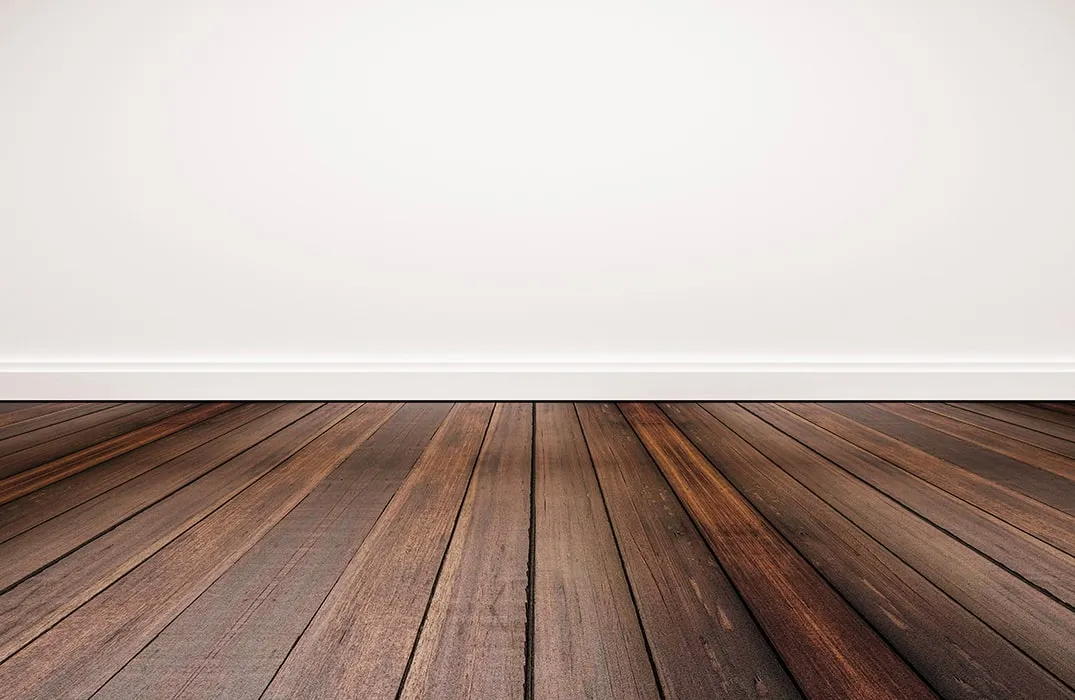 An empty room with a wooden floor and a white wall.