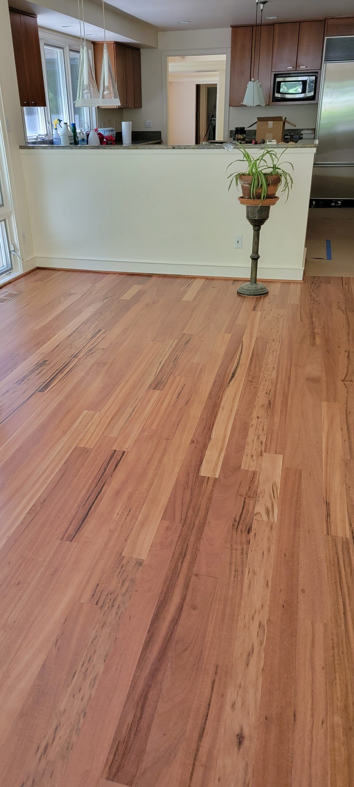 A living room with hardwood floors and a kitchen in the background.