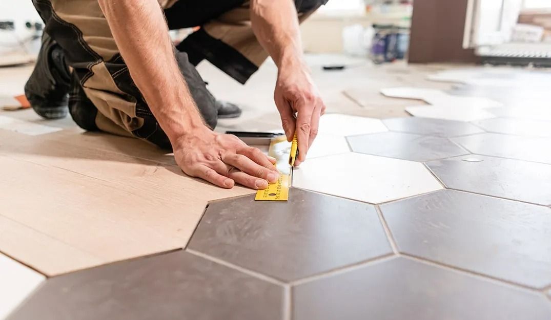 A man is measuring a tile floor with a ruler.