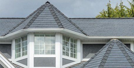 A house with a slate roof and a bay window.