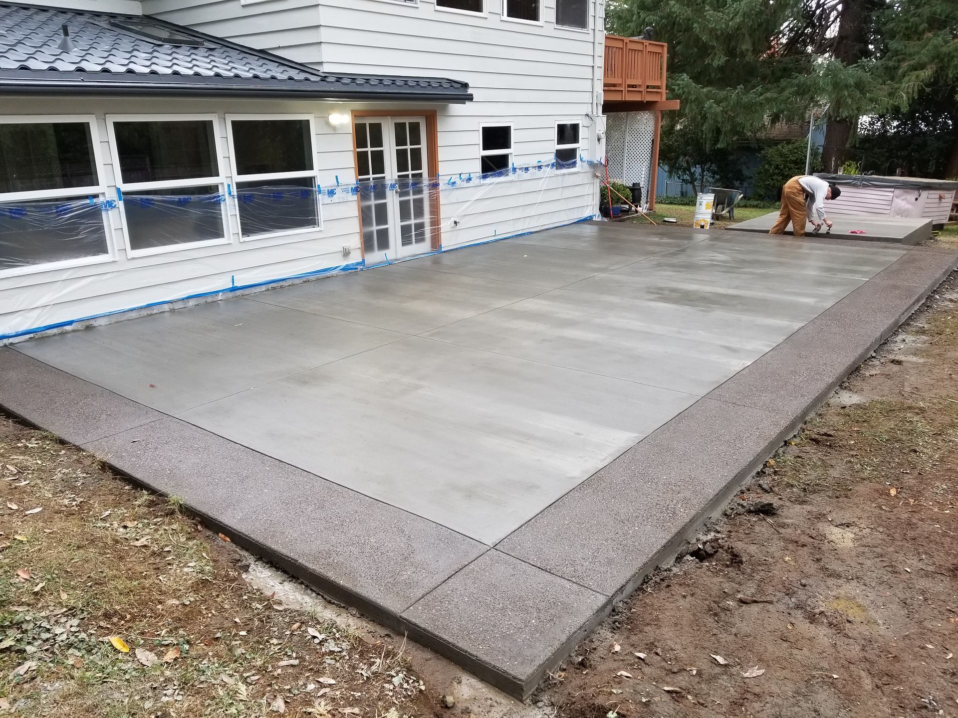 New concrete patio beside a house with a raised stone border