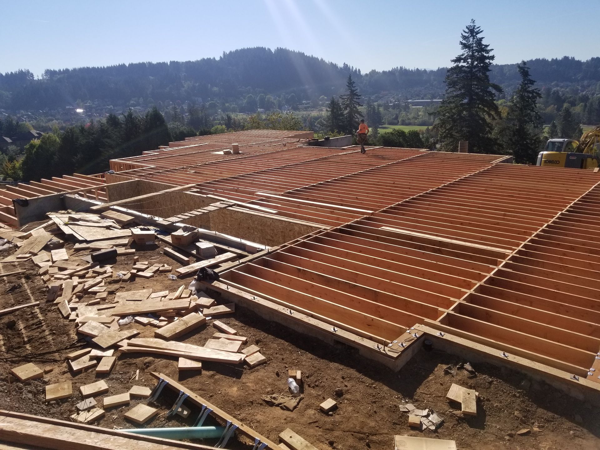 Rooftop under construction with stacked tiles, exposed beams, and hills in the background