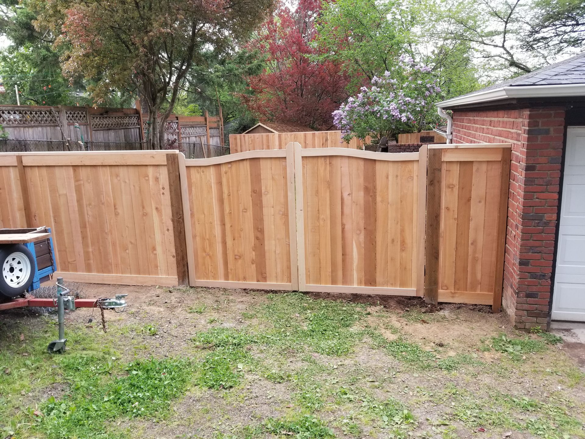 Wooden privacy fence with matching gate beside a brick garage in a backyard