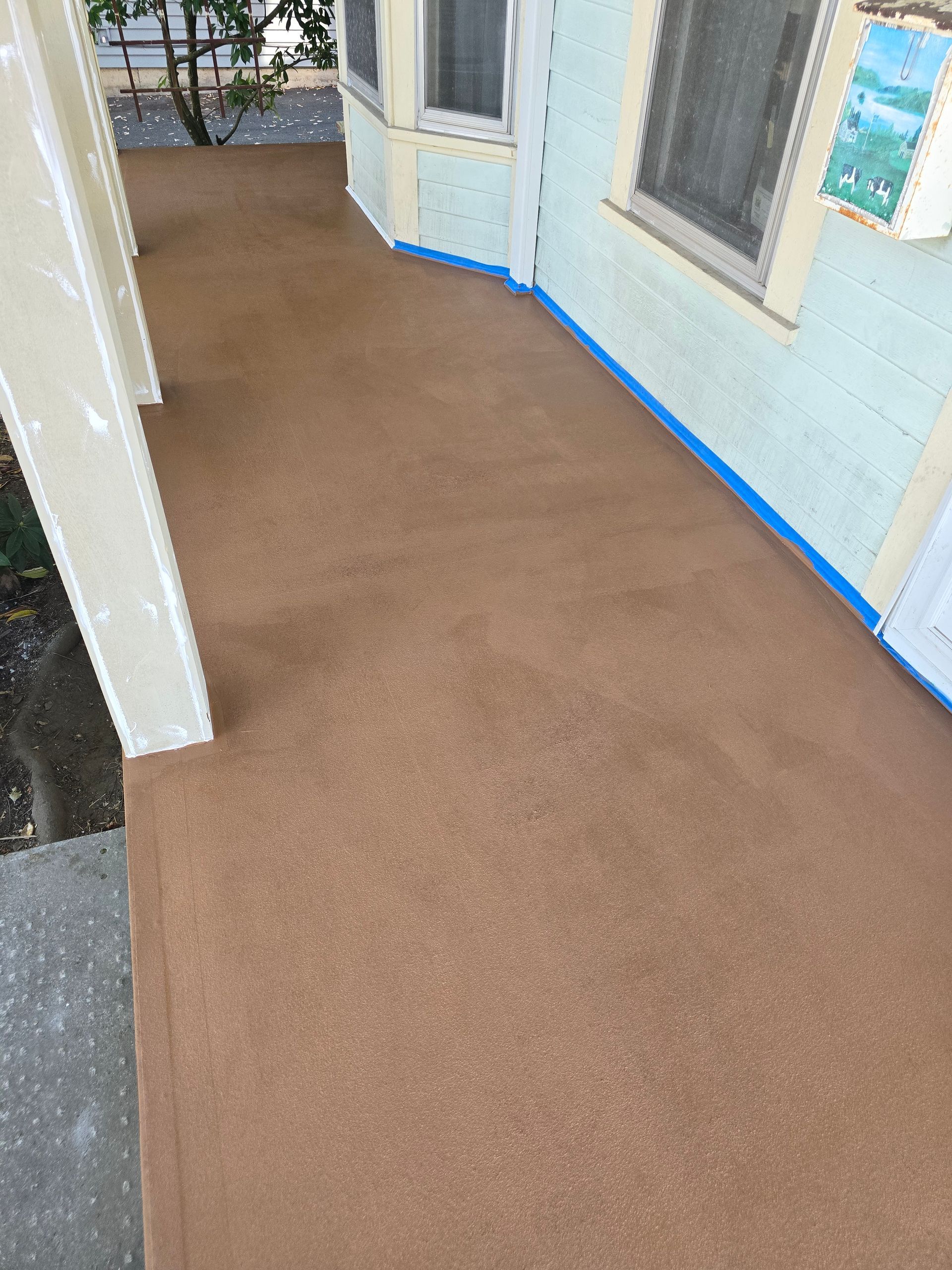 Covered walkway with brown carpet and light blue walls beside windows and a door