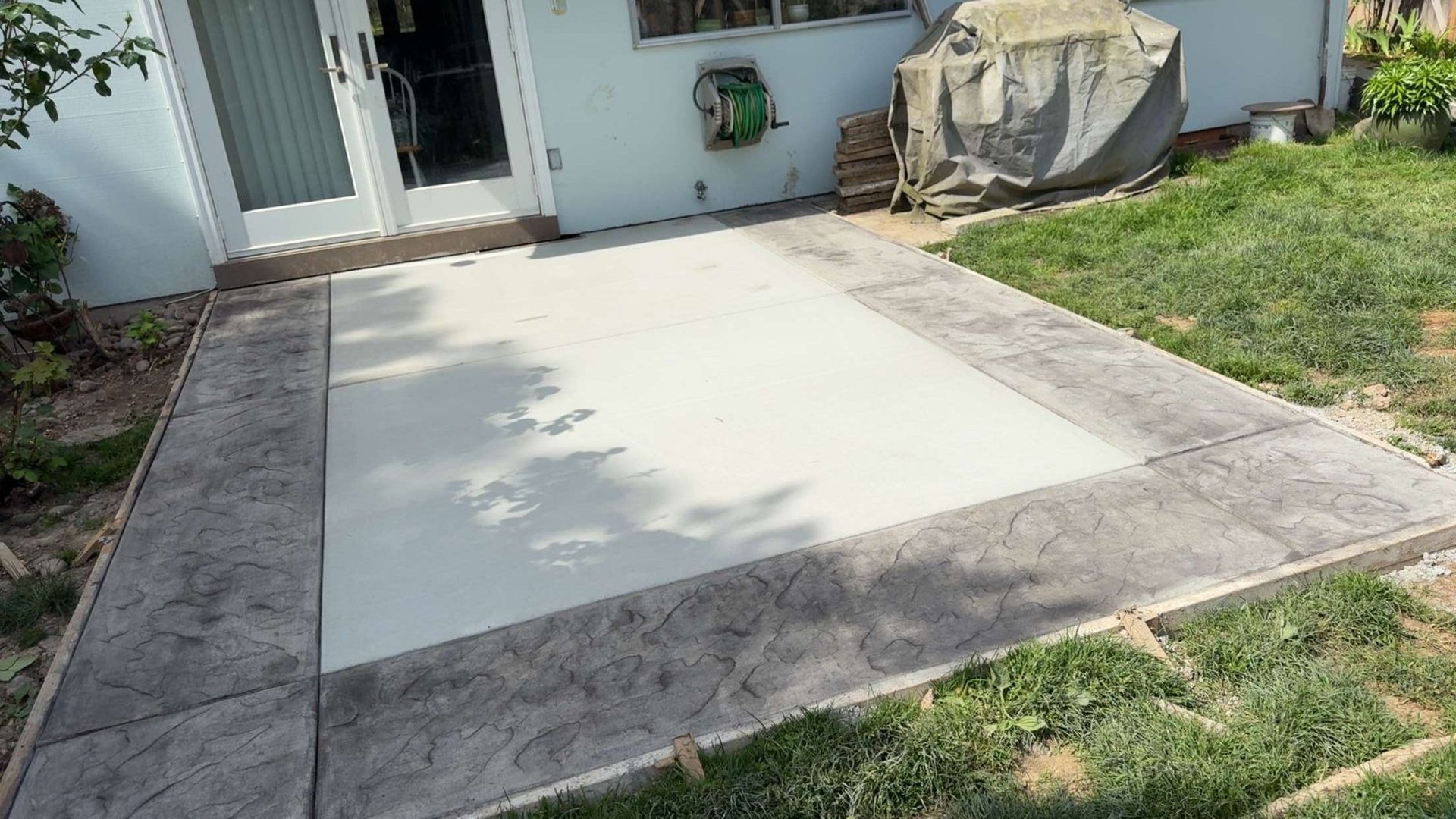 Freshly poured concrete patio slab beside a grassy yard near a house