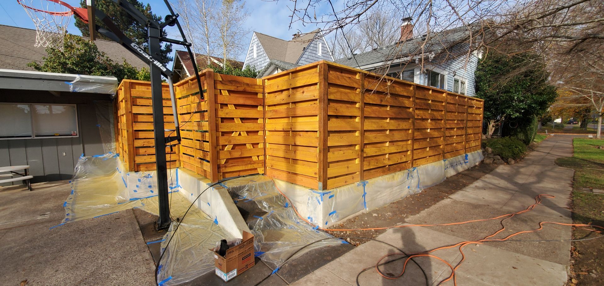 Orange wooden fence panels around a yard on a sunny day