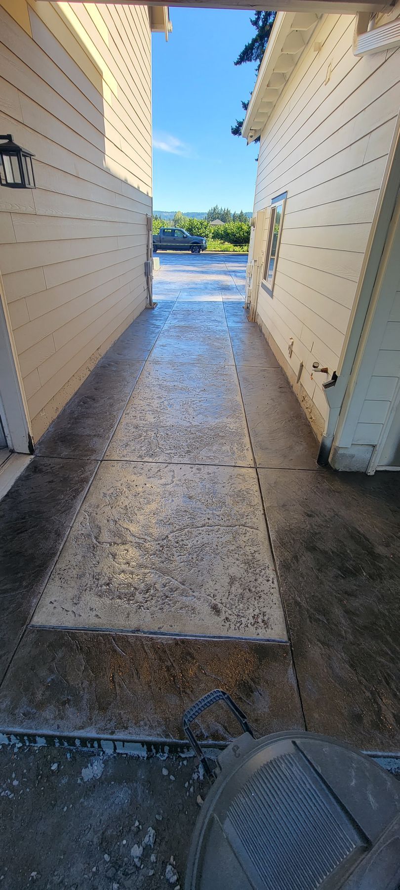 Narrow wet alley between white buildings leading to a bright outdoor street view