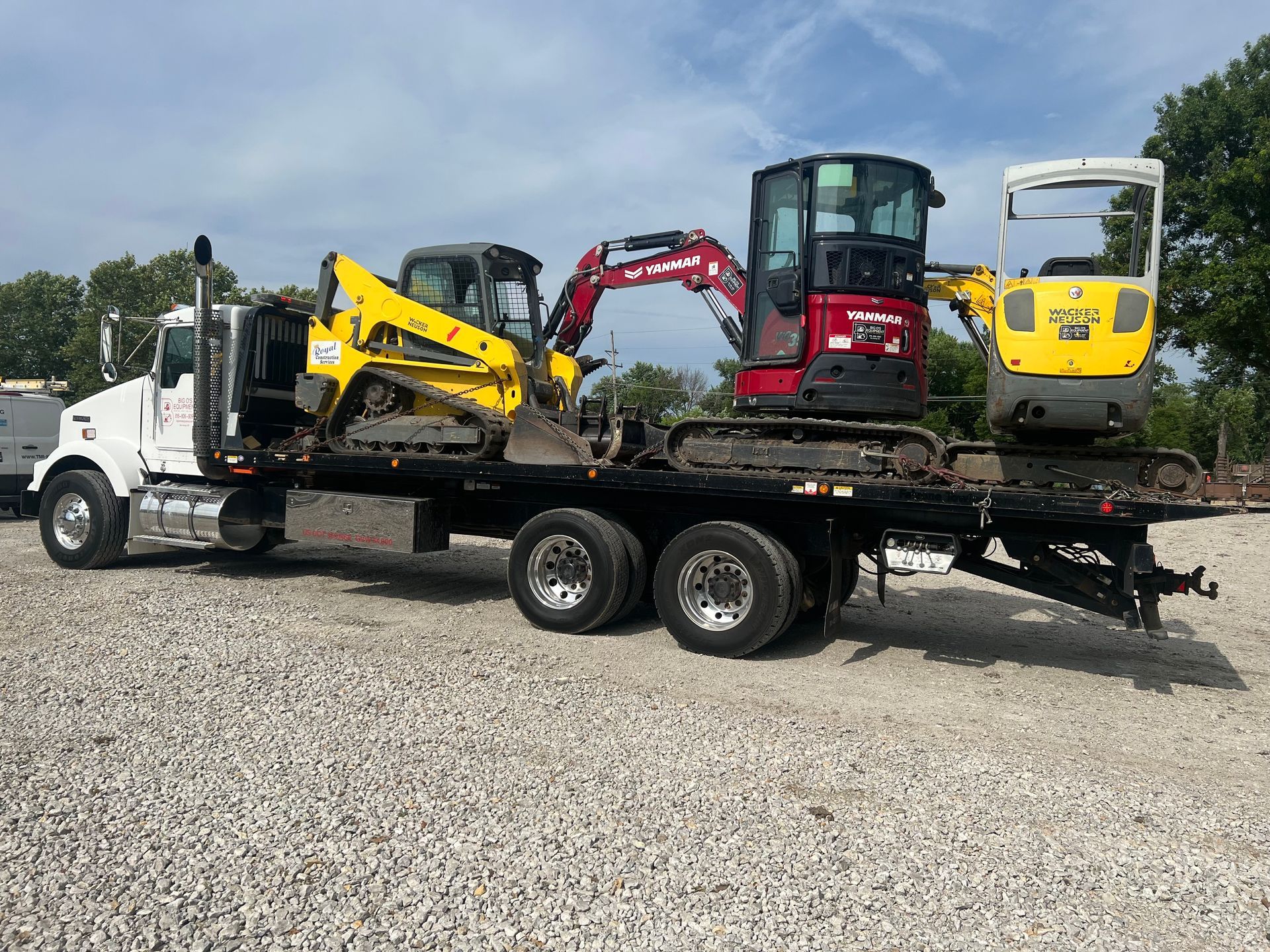 A tow truck is carrying excavators on a flatbed trailer.