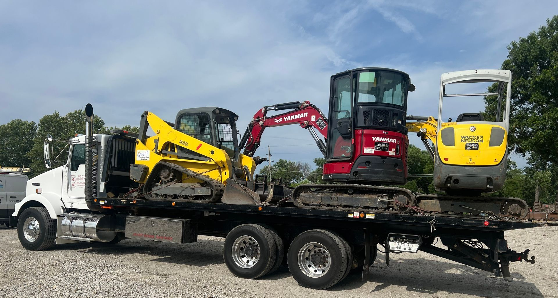 A tow truck is carrying excavators on a flatbed trailer.