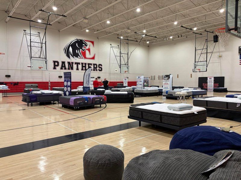 Indoor gymnasium with several folding mats set up on the floor and a large Panthers logo on the wall