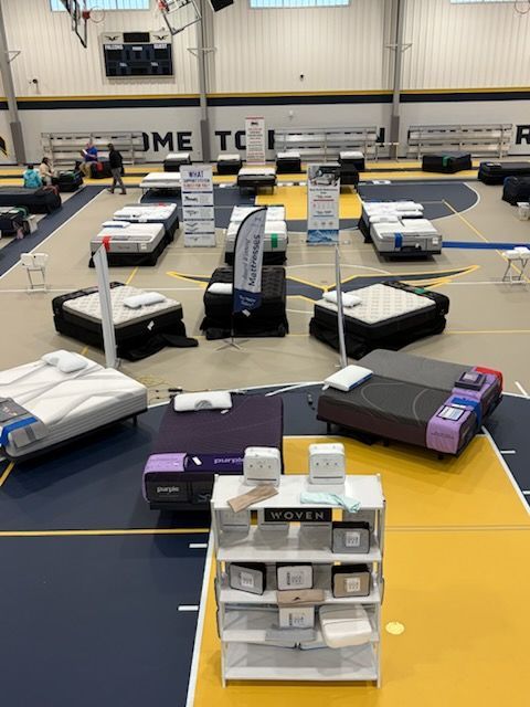 Indoor gym with several low obstacle/course stations and cushions arranged on a court with yellow boundary lines.