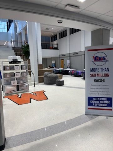 Atrium with seating, a large orange “W,” and a banner for a fundraising event by a CICS sign