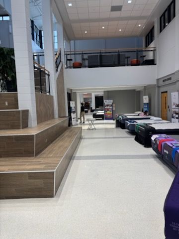Spacious modern lobby with benches, tables, and high windows under bright ceiling lights.