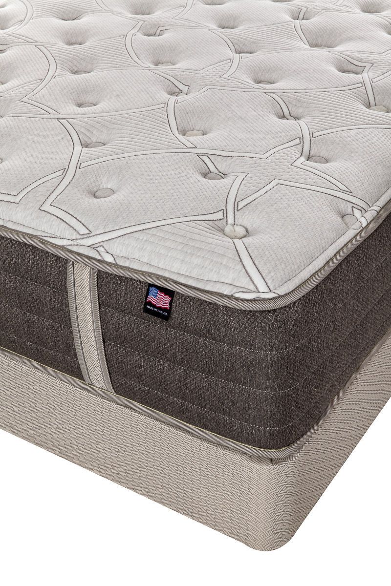 Close-up of a beige and gray upholstered mattress with a quilted top and corner label