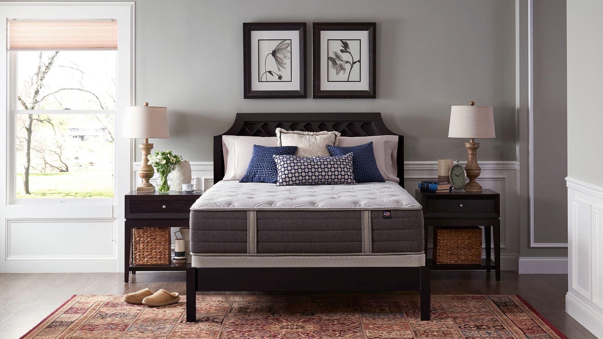 Elegant bedroom with a dark wood bed, patterned rug, matching nightstands, lamps, and framed art above the headboard