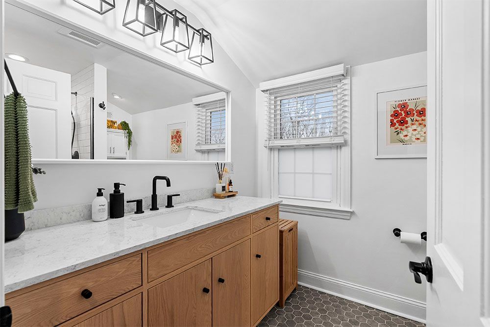 Bathroom with light wood vanity, white countertop, and gray hexagonal floor tiles.