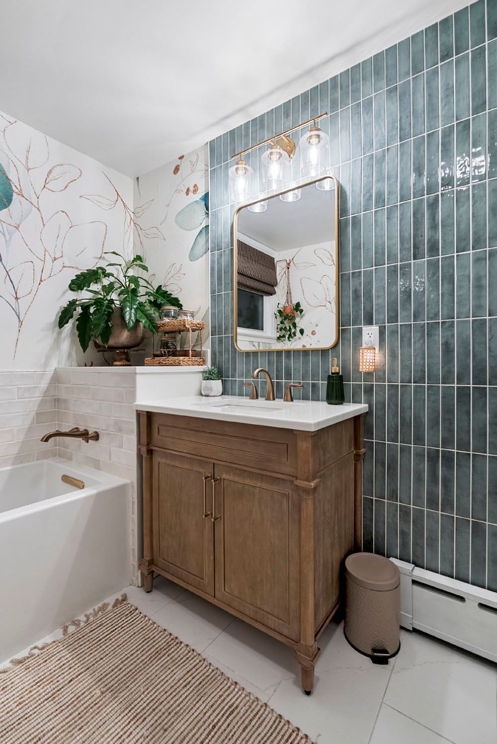 Bathroom with teal tile wall, wooden vanity, and floral wallpaper.