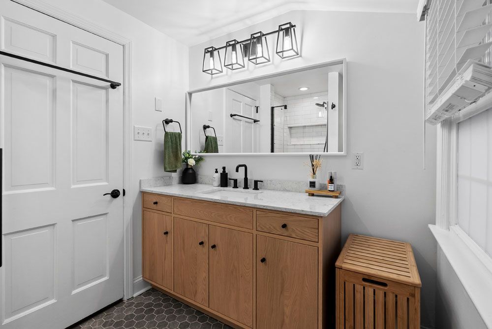Bathroom with wooden vanity, white walls, and black fixtures.