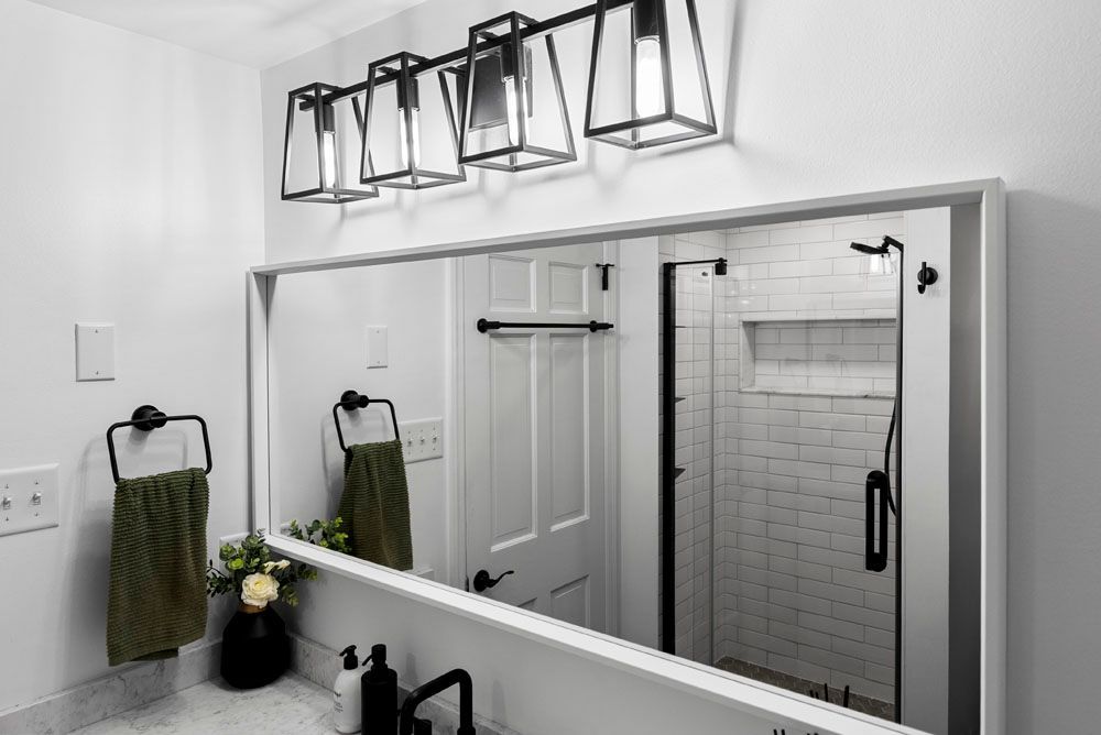 Bathroom with a large mirror, overhead black light fixture, and green towels.