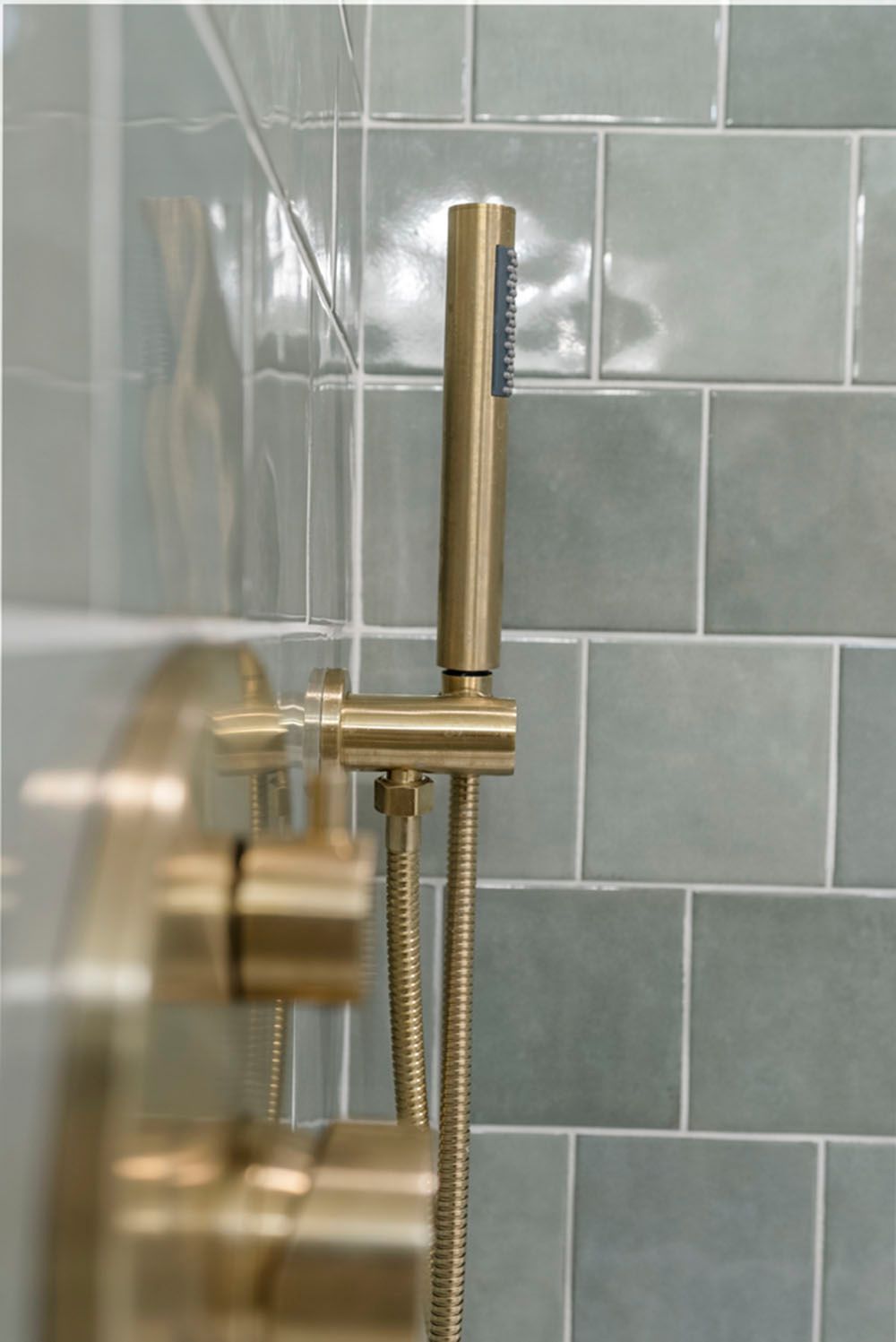 Gold showerhead and controls against blue-green tile.