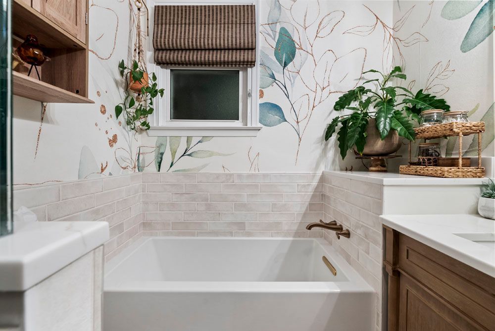 Bathroom with a bathtub, floral wallpaper, and a small window with a brown shade.