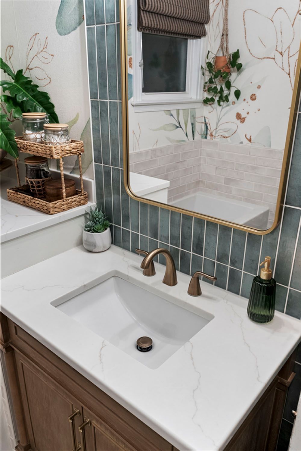 Bathroom with a white countertop, blue tile, gold-framed mirror, and wood vanity.