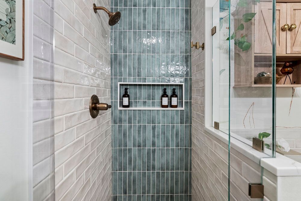 Shower with blue and beige tiled walls, bronze fixtures, and a glass door.