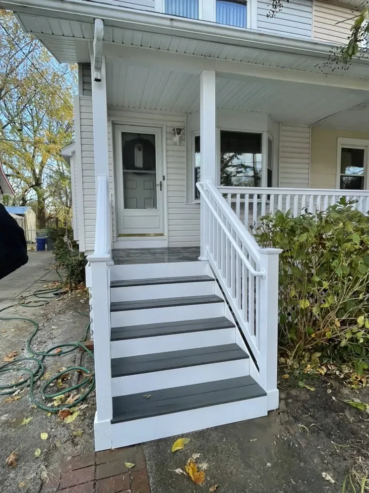 White porch with steps painted dark gray, white railings and door.