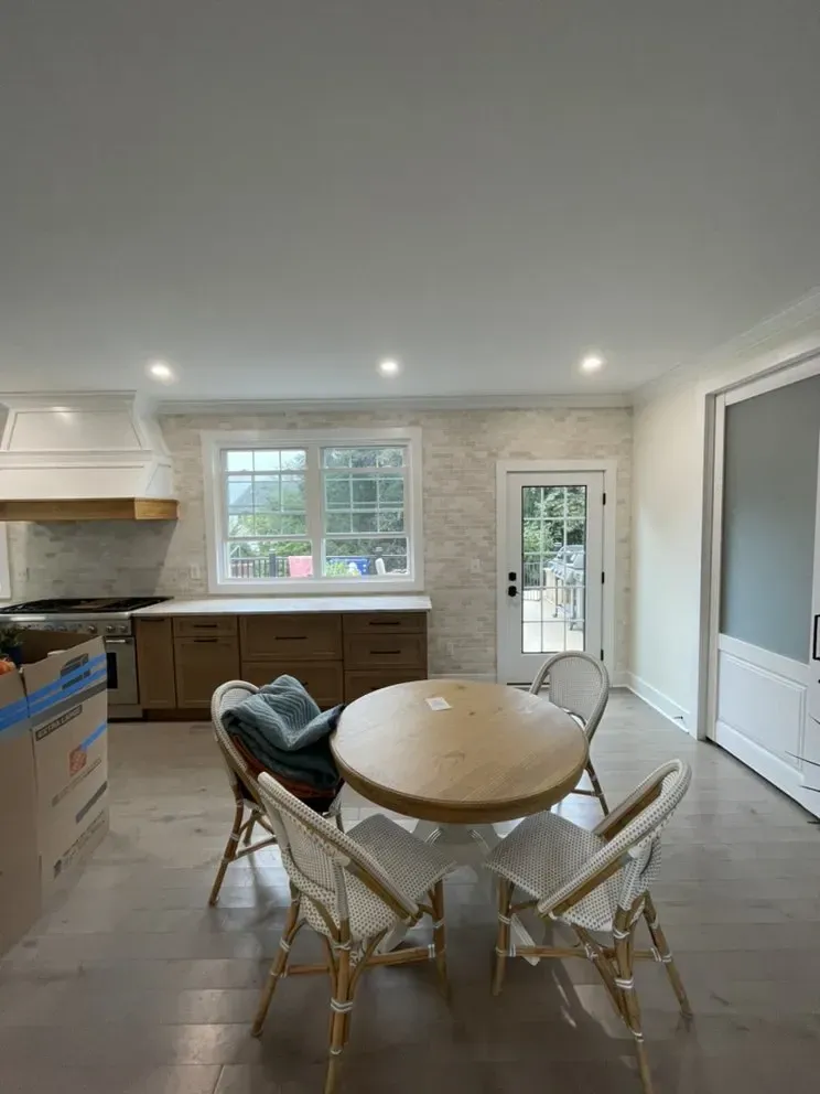 Kitchen with wooden cabinets, a round table with chairs, and a window.