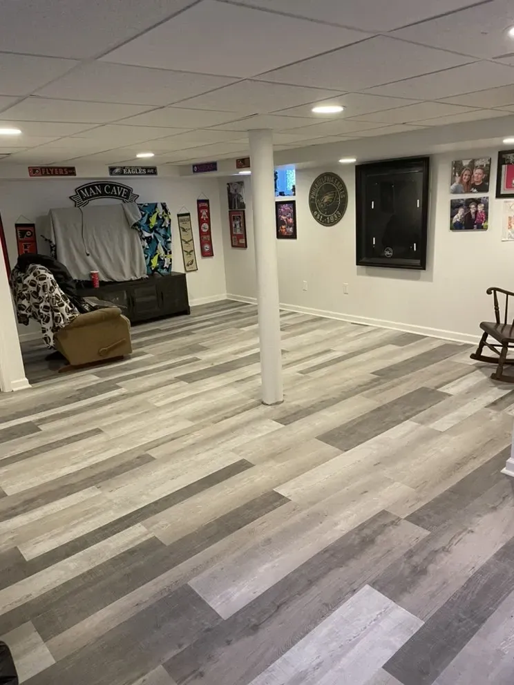 Basement with gray and white wood-look flooring, white walls, and a white support beam in the center.