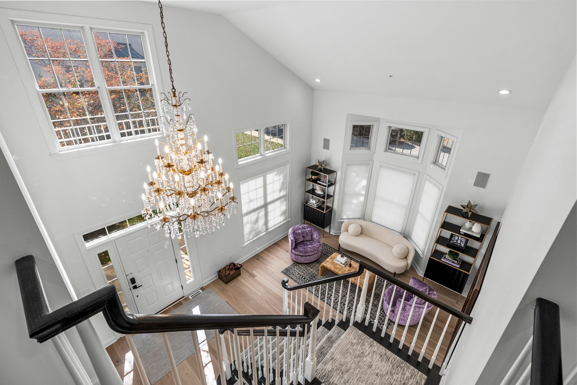 High-angle view of a bright living room with large windows, chandelier, and a curved sofa.