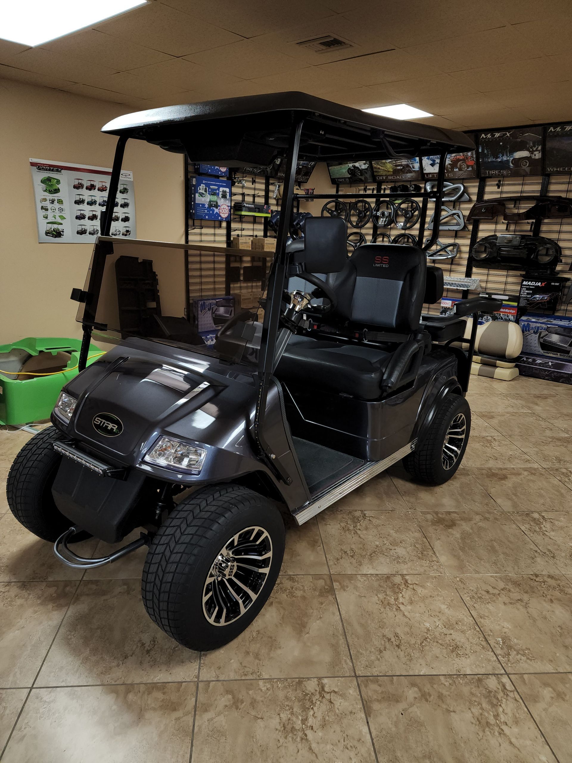 Gray golf cart with black roof and seats, indoors.