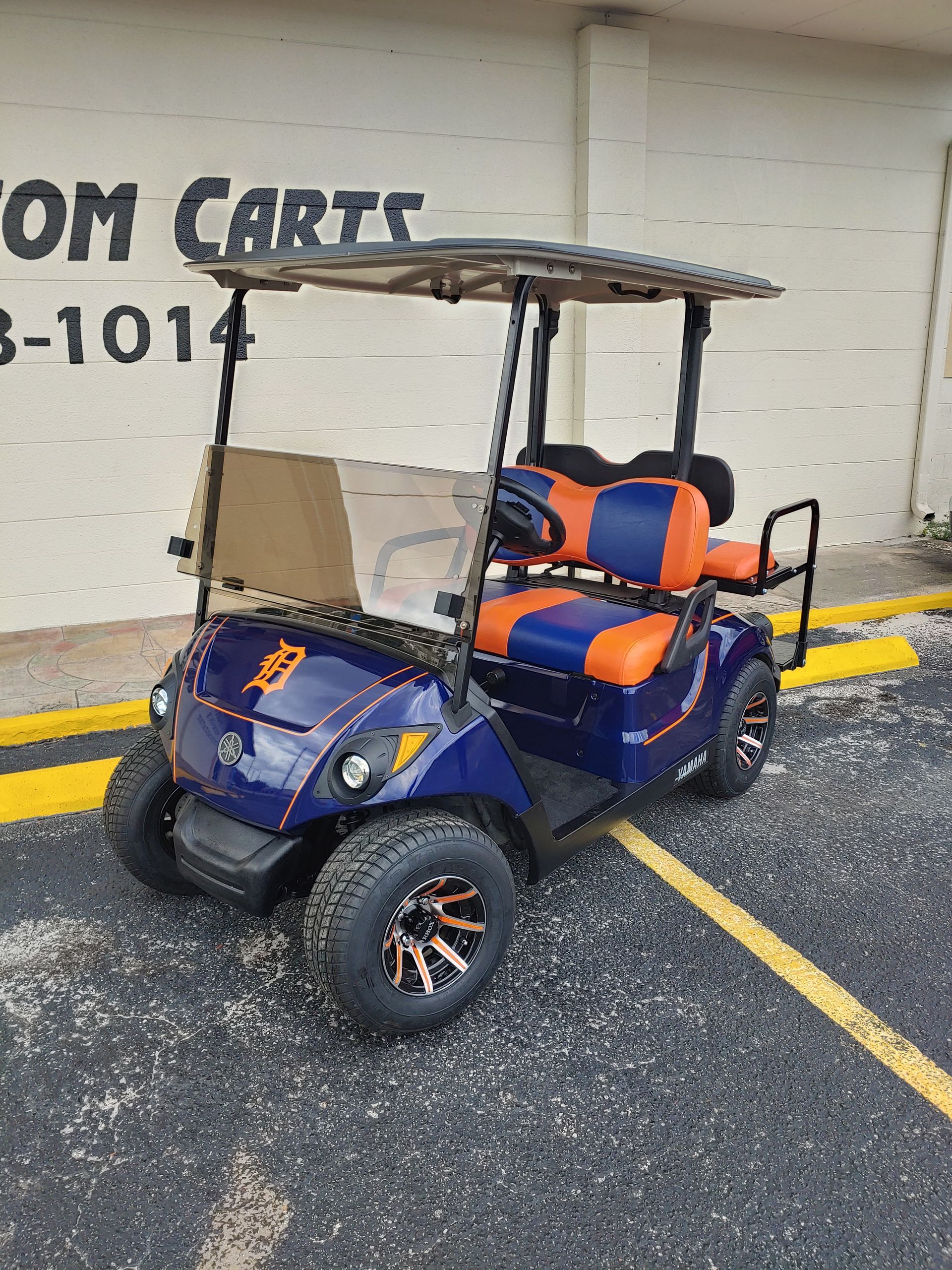 Blue and orange golf cart parked on asphalt, with 