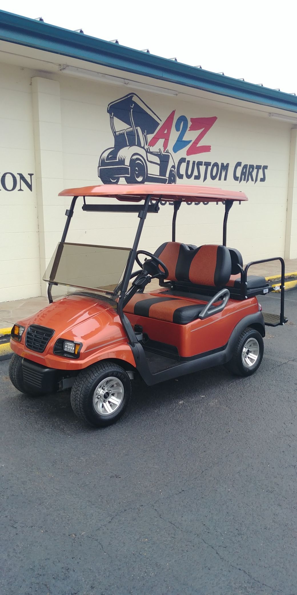 Orange golf cart parked in front of A2Z Custom Carts building.