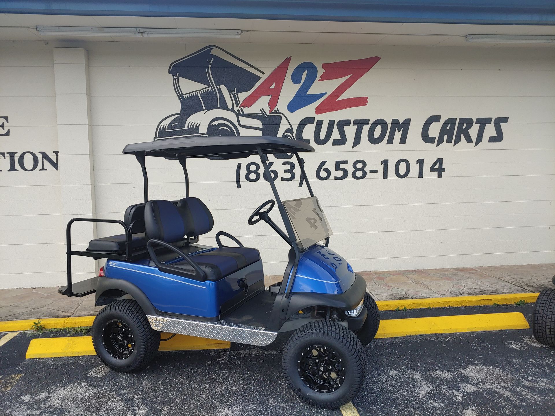 Blue golf cart with black wheels in front of 