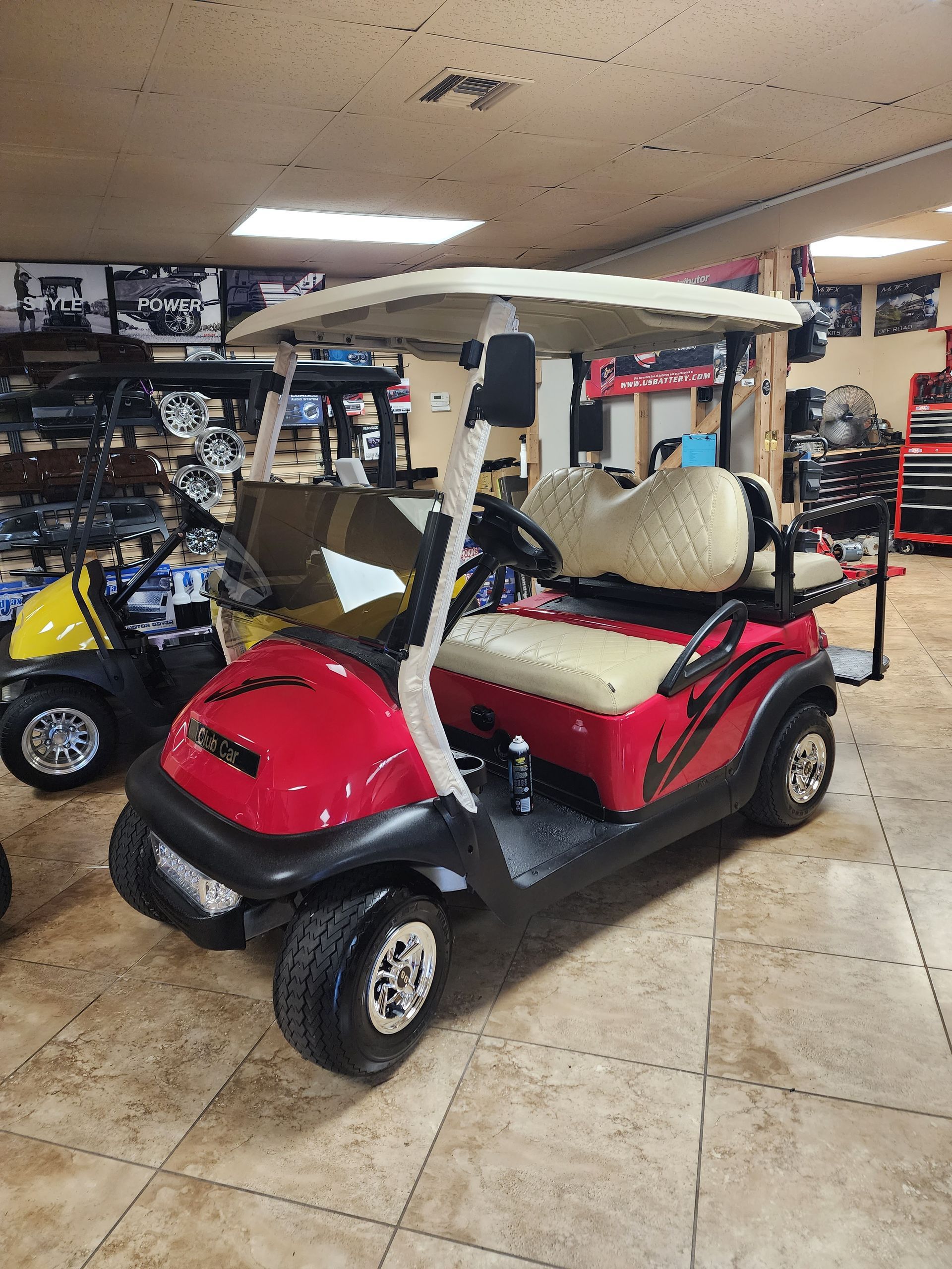Red golf cart with white roof, tan seats, inside a shop.