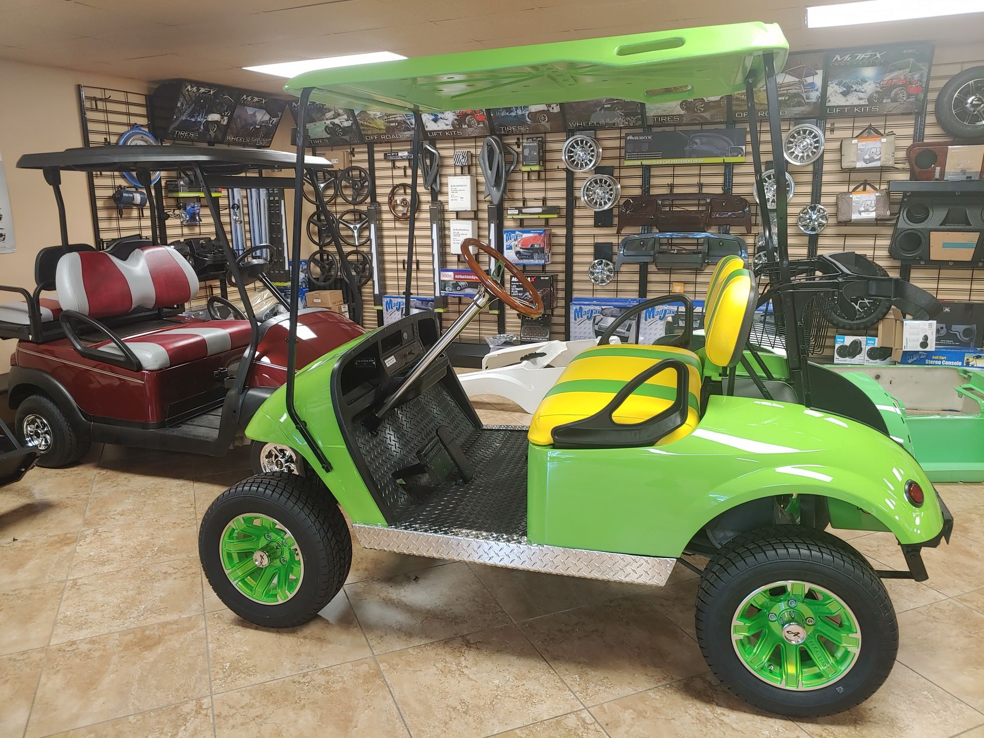 Lime green golf cart with yellow seat; inside a shop with other carts and parts.