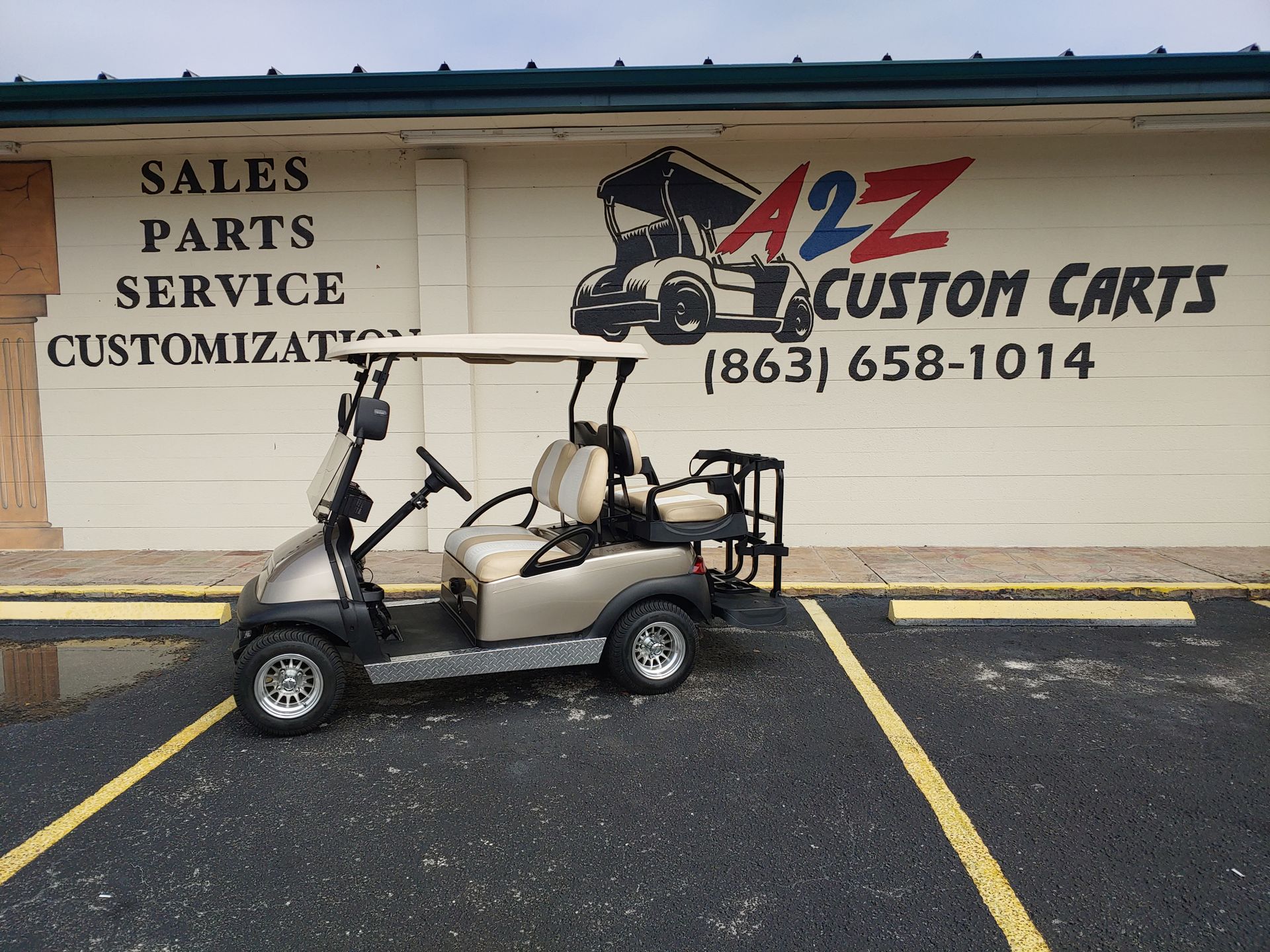 Tan golf cart parked outside a business called A2Z Custom Carts.