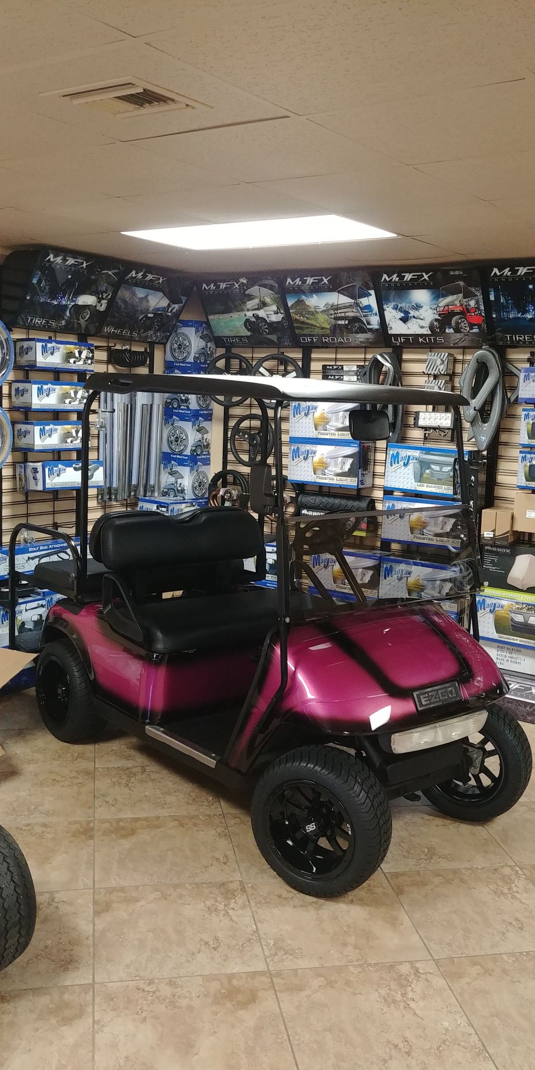 Pink golf cart with black wheels, parked in a store.