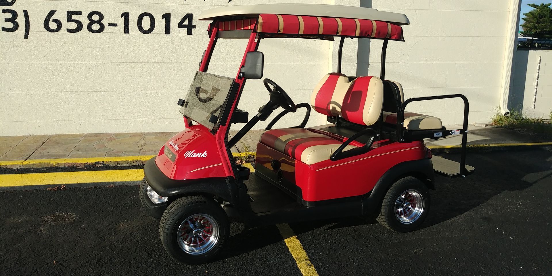 Red golf cart with white and red seats, parked in front of a building.
