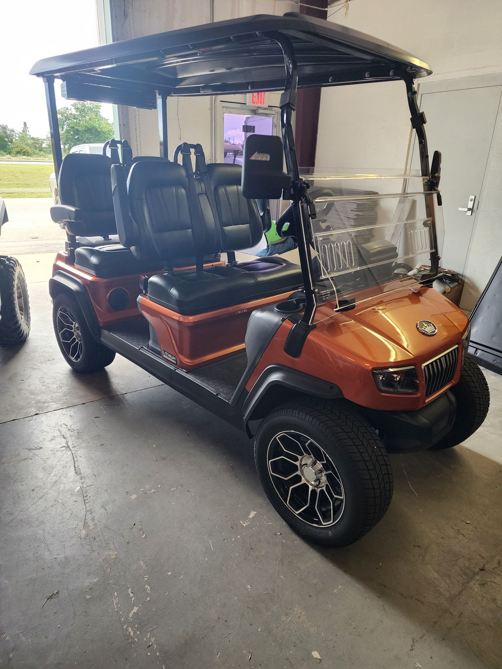 Orange golf cart with black roof and wheels, parked inside a garage.