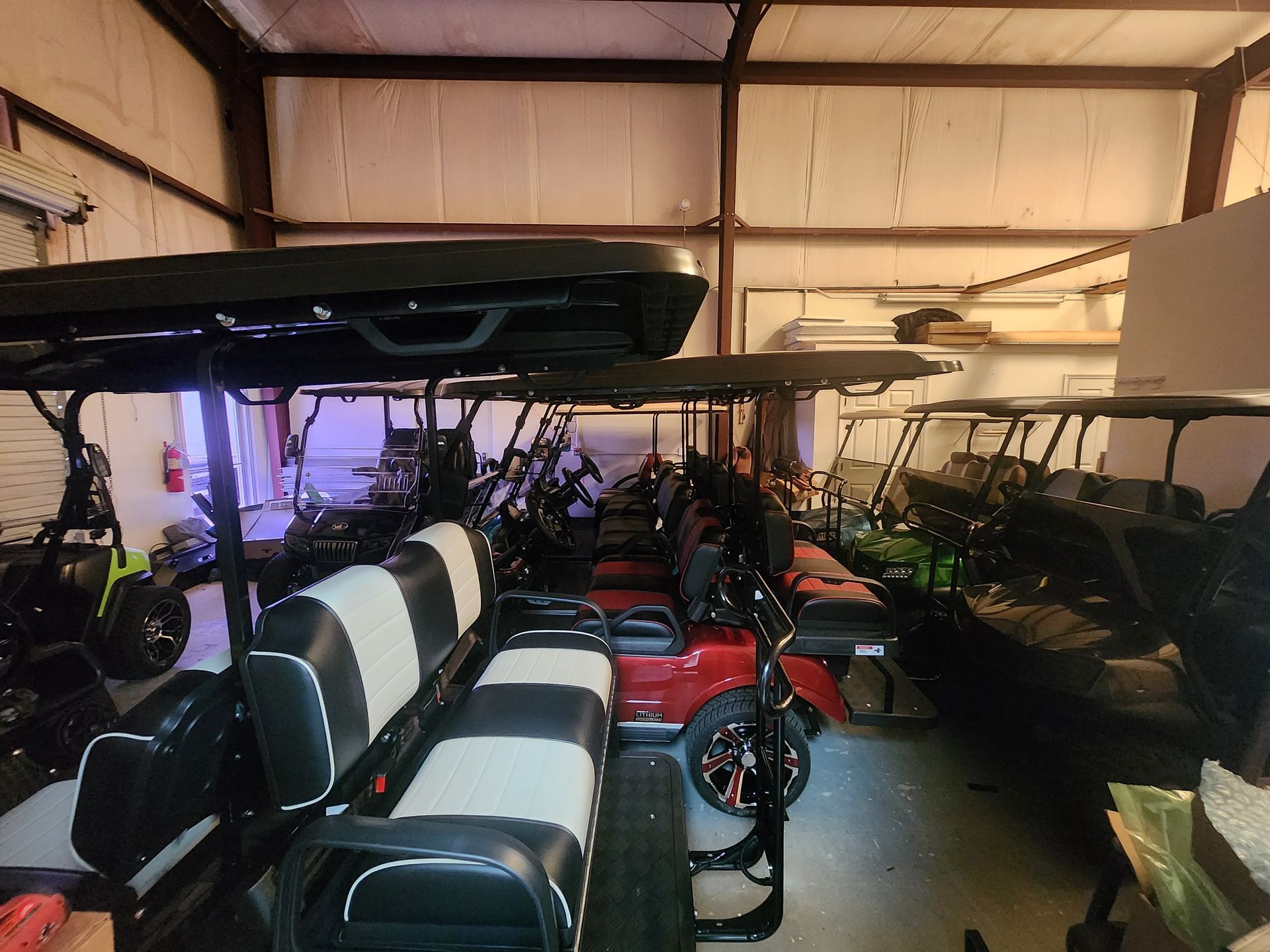 Golf carts parked inside a garage. Several red, black, and green carts are visible.