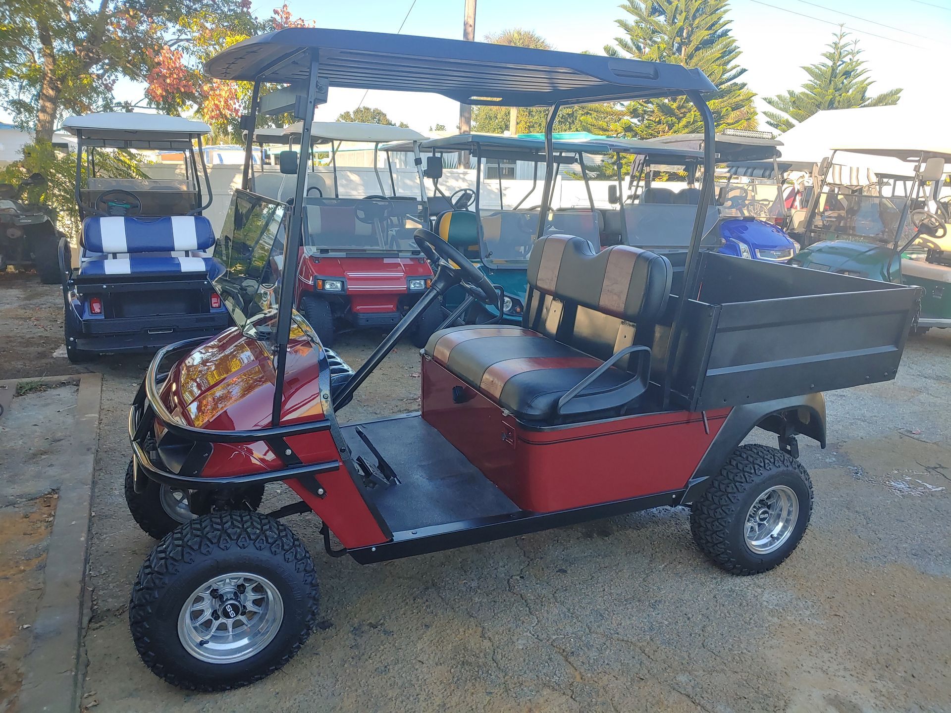 Red golf cart with a utility bed, parked outside.