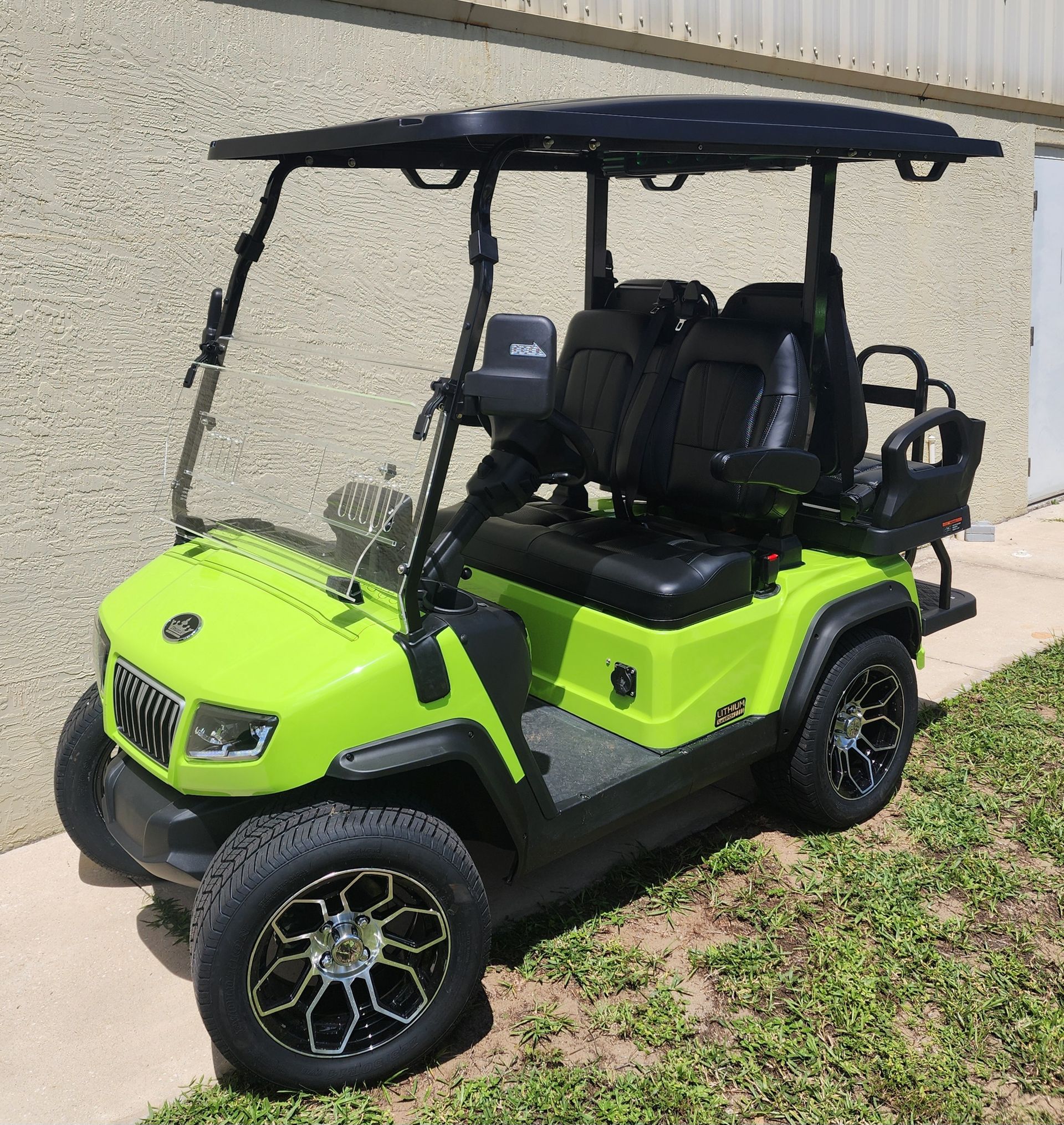Lime green golf cart with black roof, seats, and wheels, parked outdoors.
