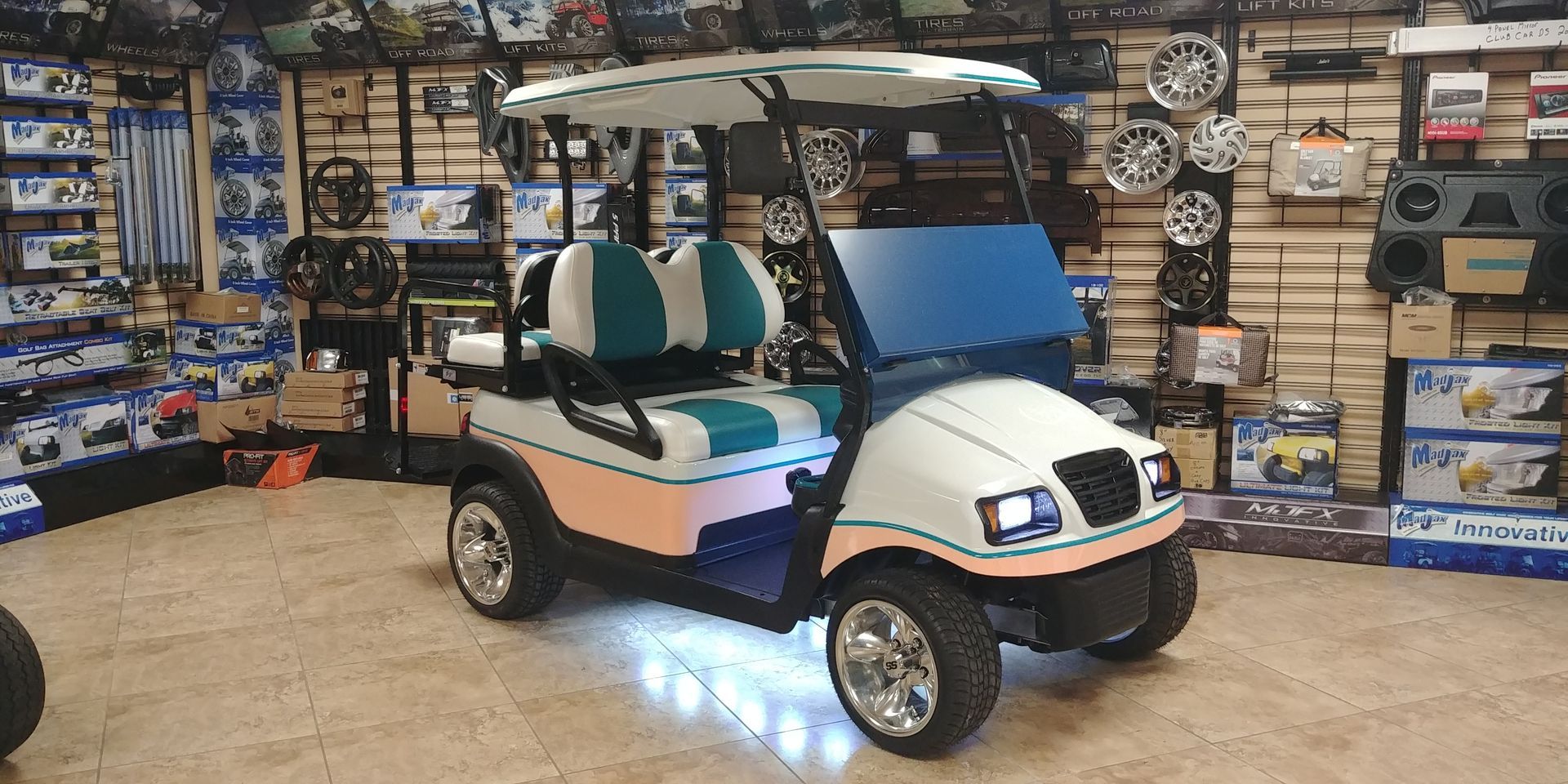 White golf cart with teal accents in a shop.