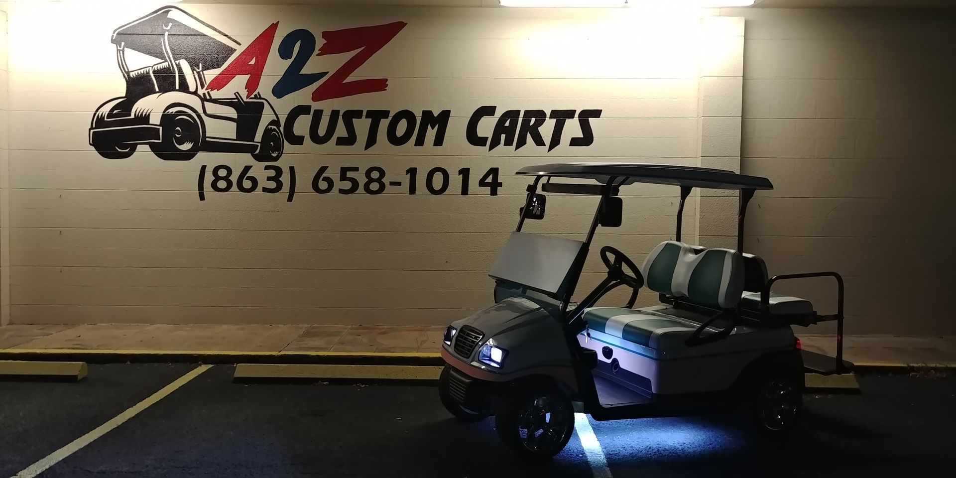 A golf cart parked in front of a wall with the business logo 